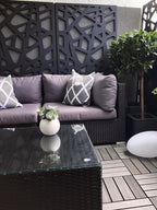 Outdoor wicker patio sofa with gray cushions and dark woven coffee table