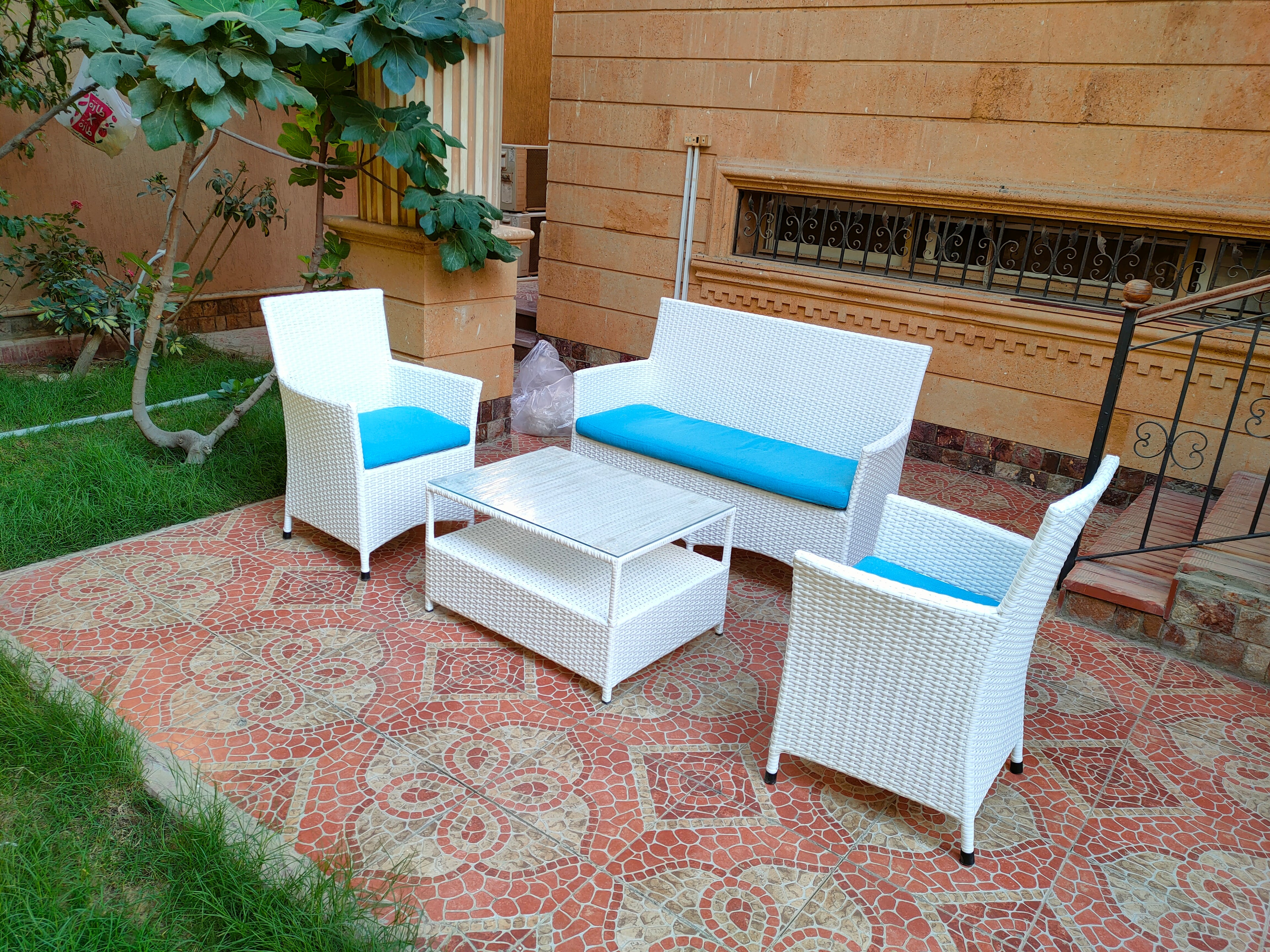 4-piece outdoor furniture set with white wicker-style chairs, blue cushions, and ottoman