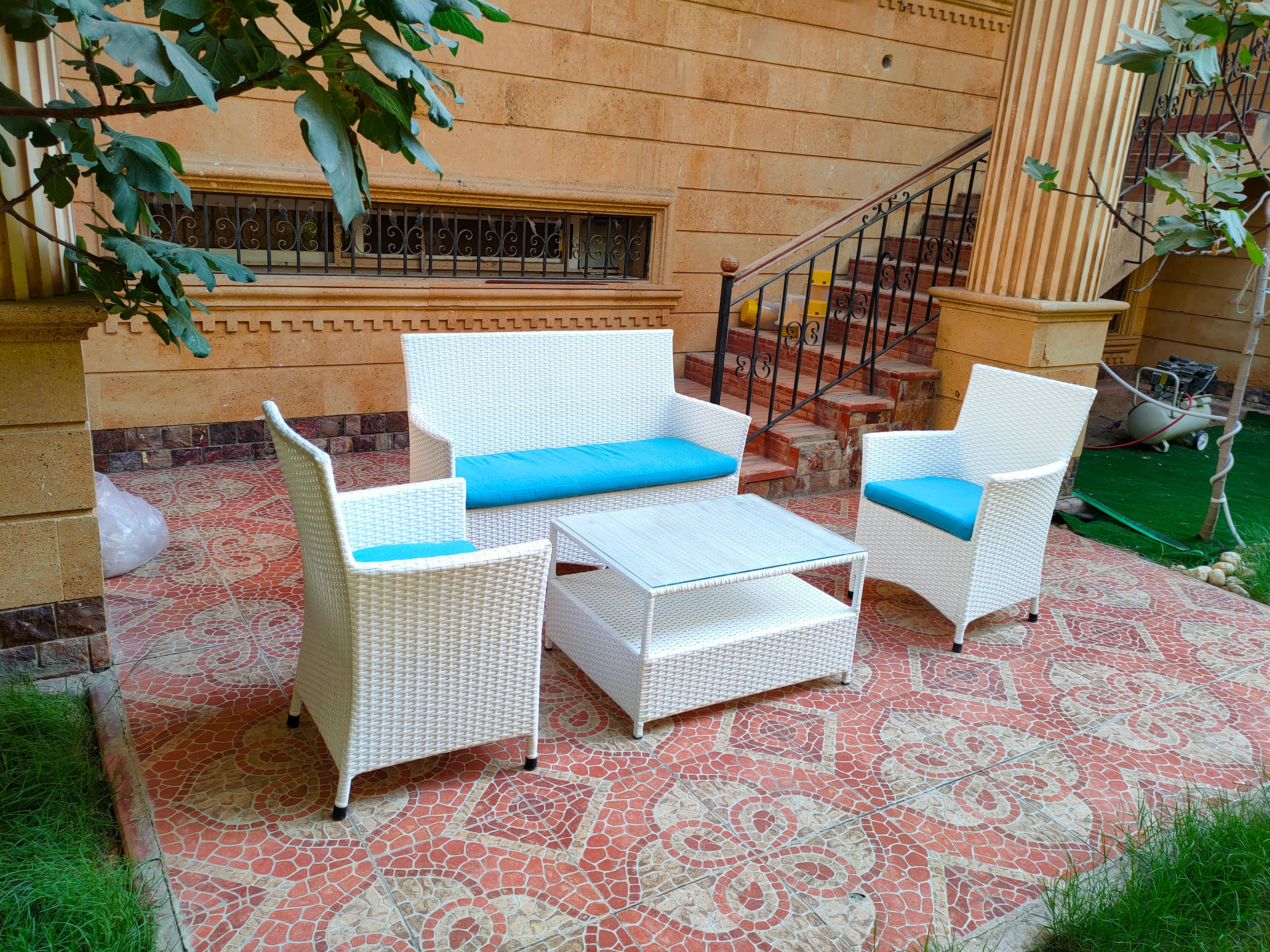 Outdoor 4-piece patio set: two blue-cushion chairs, loveseat, and white ottoman