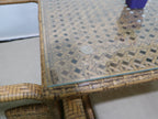 Woven rattan outdoor table with glass top and corner frame detail