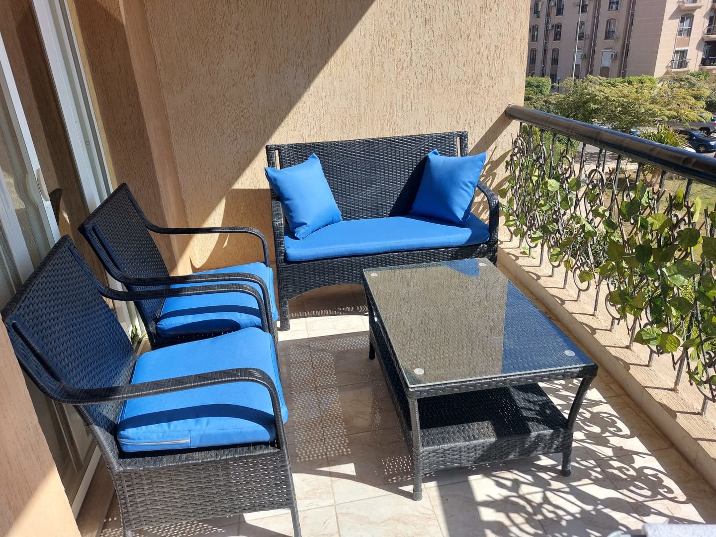 Rattan balcony seating set with blue cushions, loveseat, two chairs, coffee table