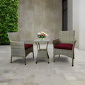 Outdoor furniture set with two woven armchairs, red cushions, and a rectangular glass-top table